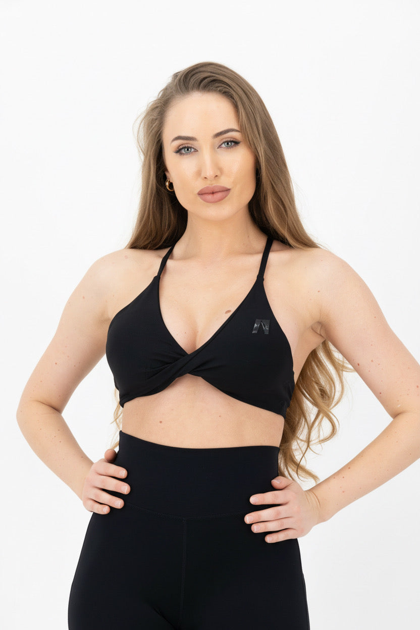 Woman wearing a black sports bra and leggings on a white background