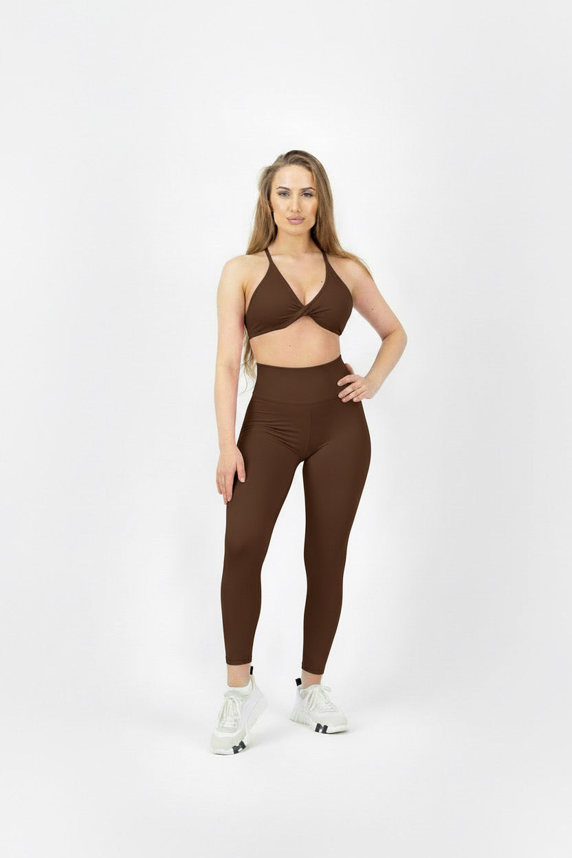 Woman wearing a brown sports bra and leggings set on a white background