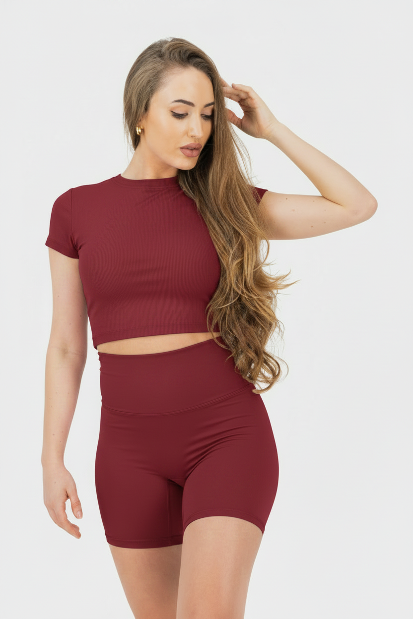 Woman wearing a dark red athletic outfit on a white background