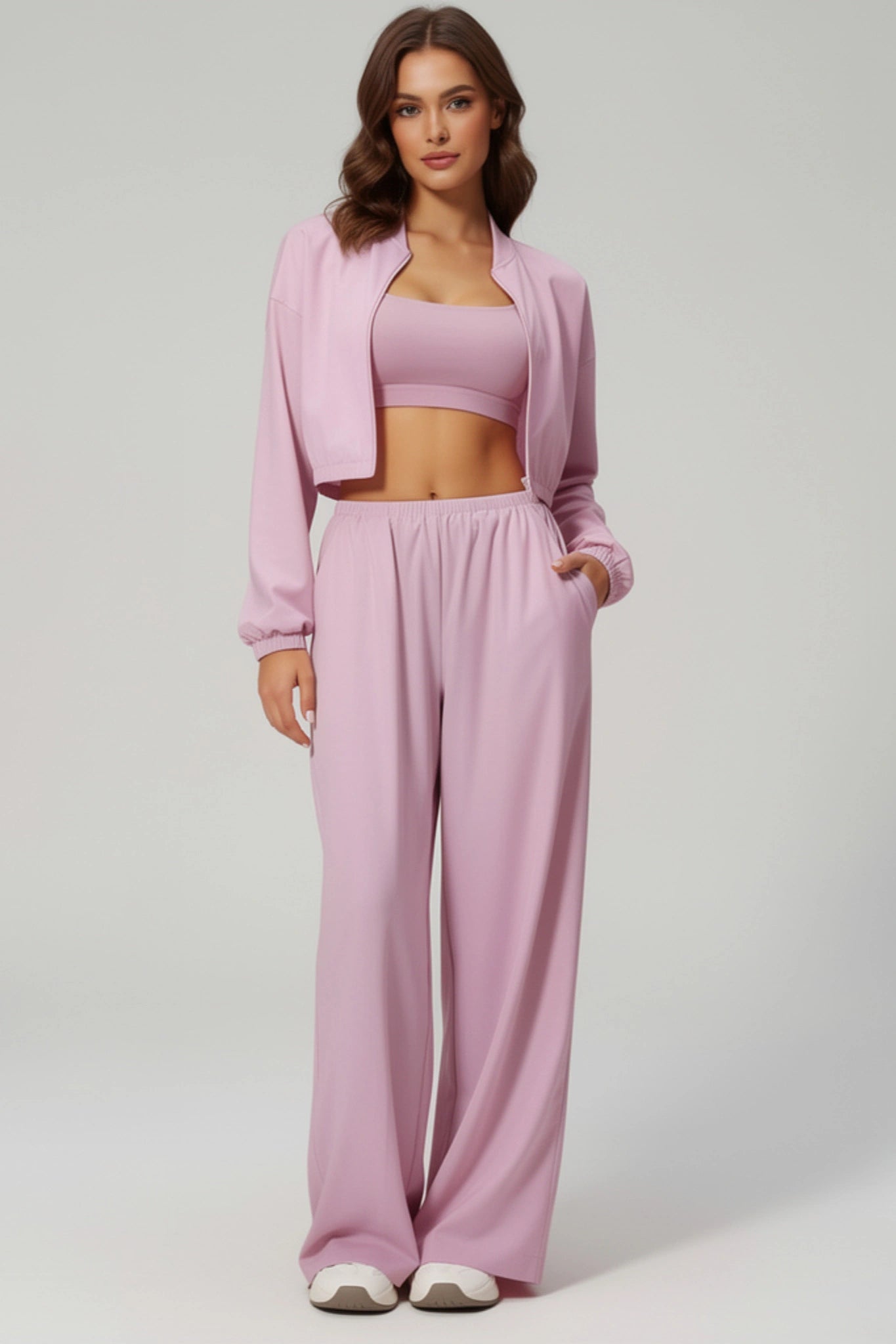 Woman wearing a pink outfit with a jacket, top, and pants on a white background